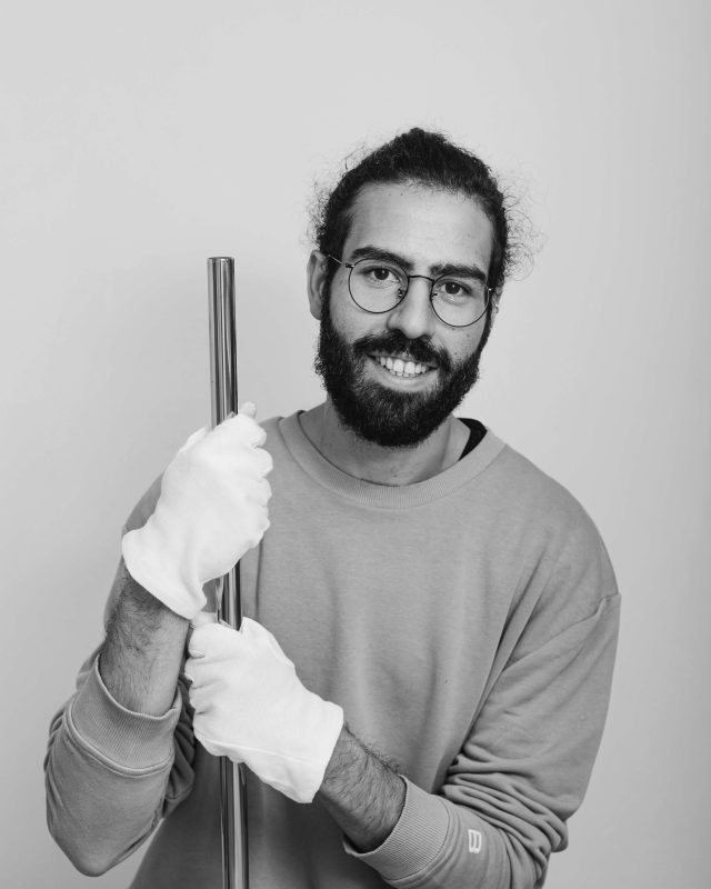 gözlüklü ve sakallı elinde eldiven ile bakır boru tutan bir genç erkek siyah beyaz portre fotoğrafı