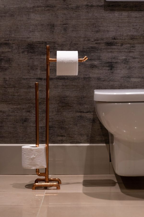 tuvaletin yanında yerde duran bakır tuvalet kağıtlık üzerinde 2 adet beyaz tuvalet kağıdı iç mekan kullanım
